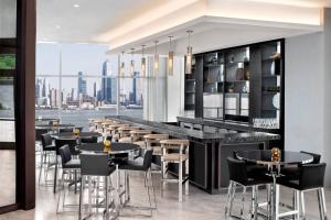 a restaurant with a bar with a view of the city at Envue, Autograph Collection in Weehawken