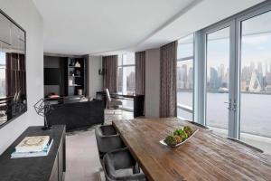 a living room with a dining table and a large window at Envue, Autograph Collection in Weehawken