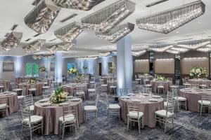 a banquet hall with tables and chairs and chandeliers at Envue, Autograph Collection in Weehawken