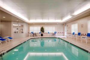 a swimming pool with blue chairs and tables in a room at Residence Inn by Marriott Portsmouth in Portsmouth