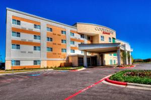 a building with a parking lot in front of it at Courtyard by Marriott San Marcos in San Marcos