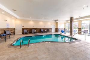 einen Pool in einer Hotellobby mit Stühlen und Tischen in der Unterkunft Fairfield Inn & Suites by Marriott Gainesville I-35 in Gainesville