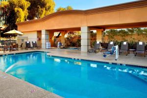 a swimming pool in a hotel with chairs and umbrellas at Fairfield Inn & Suites Phoenix Midtown in Phoenix