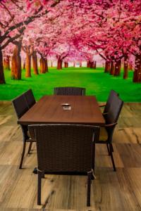 une table en bois avec deux chaises et des arbres roses dans l'établissement DURAZNO INN, à Nuevo Casas Grandes