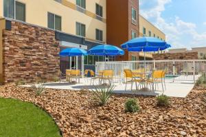 un patio con mesas y sillas y sombrillas azules en Fairfield Inn & Suites by Marriott Cotulla, en Cotulla