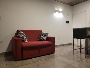 una silla roja con 2 almohadas en una habitación en Los Naranjos en San Salvador de Jujuy