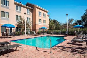 una piscina en un hotel con mesas y sombrillas en Fairfield Inn and Suites by Marriott Lakeland Plant City, en Plant City