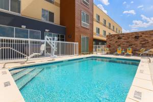 una piscina con sillas y un edificio en Fairfield Inn & Suites by Marriott Cotulla, en Cotulla