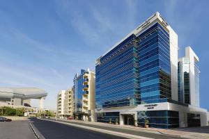 ein hohes Gebäude mit blauen Fenstern auf einer Straße in der Unterkunft Courtyard by Marriott Dubai, Al Barsha in Dubai