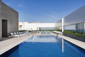 una piscina con sillas blancas y un edificio en Courtyard by Marriott Dubai, Al Barsha, en Dubái