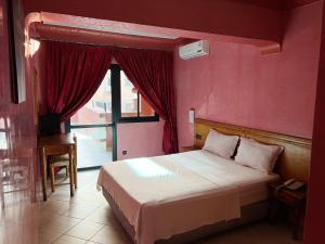 a bedroom with a bed with a red wall and a window at Hotel Majorelle in Marrakech