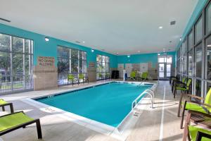 a large swimming pool in a hotel room with green chairs at SpringHill Suites by Marriott Orangeburg in Orangeburg