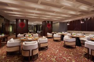 uma sala de jantar com mesas e cadeiras brancas em Ningbo Marriott Hotel em Ningbo