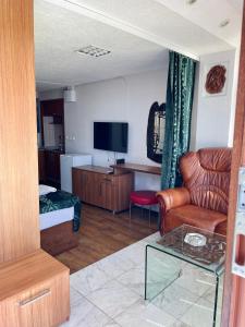 a living room with a couch a chair and a television at Studio By the Lake in Ohrid