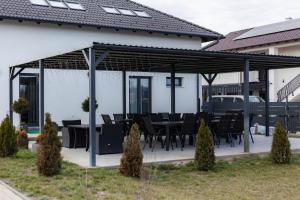 a pavilion with black tables and chairs in a yard at Laura Apartmanház in Mórahalom