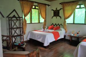 Un dormitorio con una cama con almohadas rojas. en Suchipakari Amazon Eco -Lodge & Jungle Reserve en Puerto Misahuallí