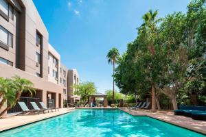 una piscina en un hotel con sillas y árboles en SpringHill Suites Scottsdale North en Scottsdale