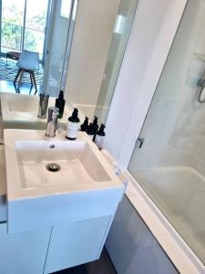 a white bathroom with a sink and a shower at Aspendale Beach Escape -Walk To Mordialloc in Aspendale