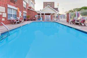 uma piscina com cadeiras e um edifício em TownePlace Suites Minneapolis West/St. Louis Park em Saint Louis Park