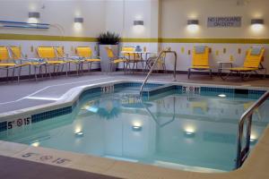 a swimming pool with yellow chairs and tables in a hotel room at Fairfield Inn & Suites by Marriott Stafford Quantico in Stafford