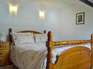 a bedroom with a wooden bed and a dresser and lights at Holly Cottage in Ystalyfera