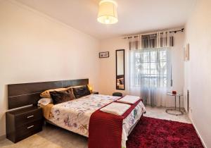 a bedroom with a large bed and a red rug at Casa da Praia, Santa Luzia in Tavira