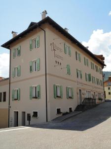 a large white building with green shuttered windows at Albergo Tuenno in Tuenno