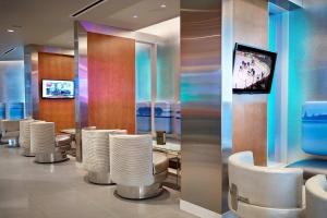 une salle d'attente avec des chaises blanches et une télévision dans l'établissement Renaissance Edmonton Airport Hotel, à Nisku