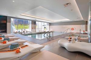 Cette grande chambre dispose d'une piscine avec des tables et des chaises. dans l'établissement Renaissance Edmonton Airport Hotel, à Nisku