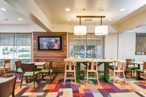 a dining room with tables and chairs and a tv at Fairfield Inn & Suites Jacksonville Airport in Jacksonville