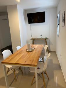 a dining room with a wooden table and white chairs at AC Departamentos in Cordoba