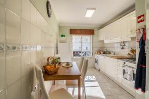 a kitchen with white cabinets and a wooden table at Casa da Praia, Santa Luzia in Tavira