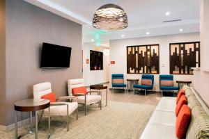 a waiting room with a couch and chairs and a tv at TownePlace Suites by Marriott Miami Homestead in Homestead