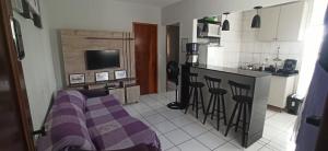 Apto com estacionamento, piscina e churrasqueira في براغانكا باوليستا: غرفة معيشة مع مطبخ مع أريكة أرجوانية