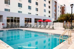 TownePlace Suites by Marriott Miami Homestead في هومستيد: مسبح وكراسي ومبنى