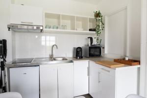 a white kitchen with a sink and a microwave at Le Havre du Daiquiri - Proche Paris in Aulnay-sous-Bois