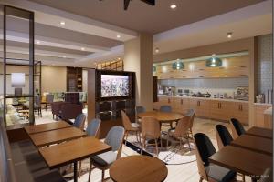 a restaurant with wooden tables and chairs and a kitchen at TownePlace Suites by Marriott New York Manhattan/Times Square in New York