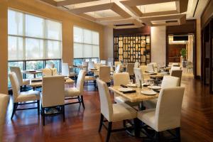 a dining room with tables and chairs and windows at Sheraton Garden Grove-Anaheim South in Anaheim