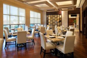 un comedor con mesas, sillas y ventanas en Sheraton Garden Grove-Anaheim South, en Anaheim