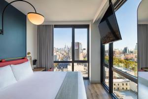 um quarto de hotel com uma cama e uma grande janela em Moxy NYC Lower East Side em Nova Iorque