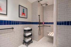 a bathroom with white and blue tiles and a shower at Moxy NYC Lower East Side in New York