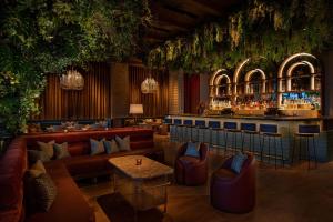 a restaurant with couches and a bar with plants at Moxy NYC Lower East Side in New York