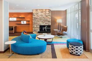 a living room with blue chairs and a fireplace at Fairfield Inn & Suites by Marriott North Bergen in North Bergen