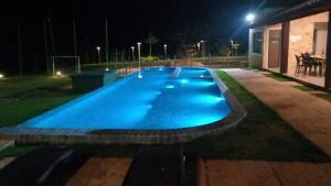 an empty swimming pool at night with lights on it at Chalé Novo - 4 quartos - 12 camas - Hidromassagem e Ar condicionado nos quartos - Cond Montserrat in Guaramiranga