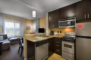 eine Küche mit Küchengeräten aus Edelstahl und ein Wohnzimmer in der Unterkunft TownePlace Suites by Marriott Rock Hill in Rock Hill