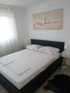 een bed met witte lakens en een foto van zeilboten bij Double Room Crikvenica 12305b in Crikvenica