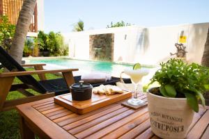a wooden table with a glass of wine and a plant at Casa Viento Hotel in Ciudad del Carmen