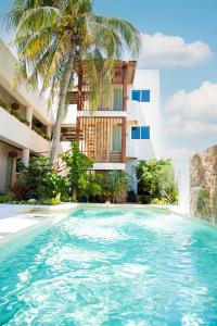 - une piscine en face d'un bâtiment avec un palmier dans l'établissement Casa Viento Hotel, à Ciudad del Carmen