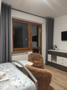 une chambre avec deux chaises, un lit et une télévision dans l'établissement Willa Ewelinka, à Zakopane
