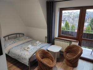 a bedroom with a bed and two chairs and a window at Willa Ewelinka in Zakopane